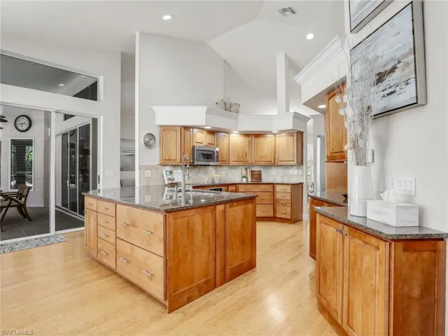 Kitchen with decorative backsplash, light wood-type flooring, stainless steel appliances, and sink
