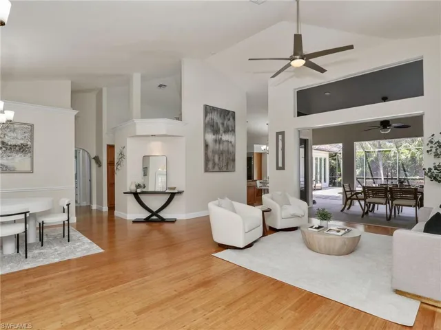 Living room featuring lofted ceiling, light hardwood / wood-style flooring, and ceiling fan with notable chandelier