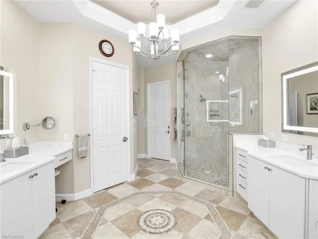 Bathroom with a notable chandelier, vanity, a shower with door, and tile patterned flooring