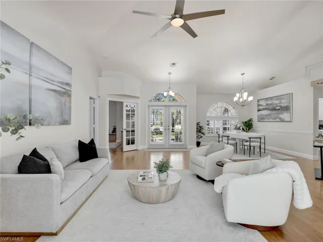 Dining room with light hardwood / wood-style flooring, ceiling fan with notable chandelier, and vaulted ceiling