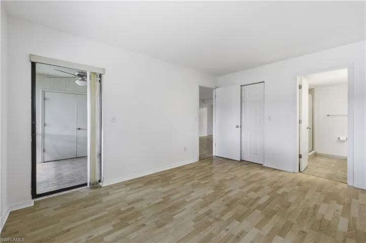 Room featuring wood-finish flooring, white walls, and a sliding glass door