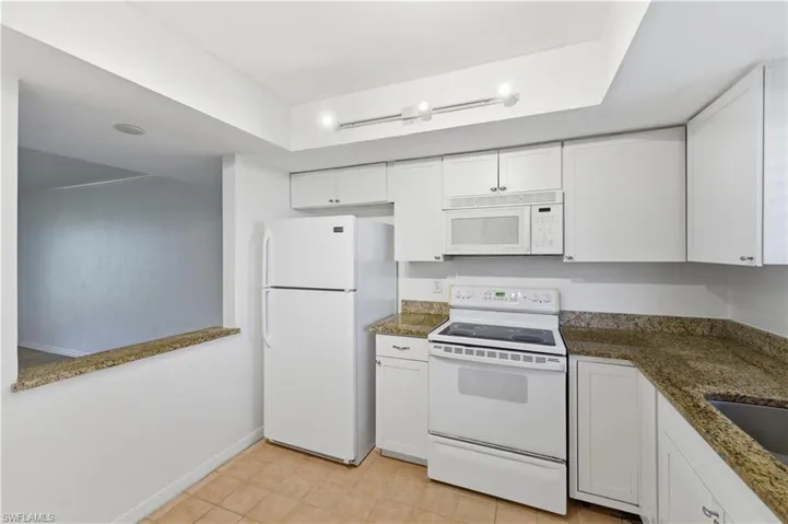 Kitchen featuring white cabinetry, a built-in microwave, an electric range, and granite countertops