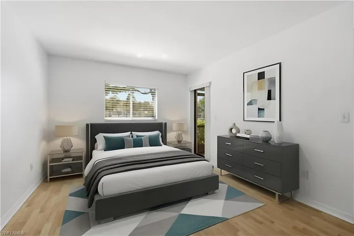 Spacious room featuring wood-finish flooring, white walls, and a window with horizontal blinds