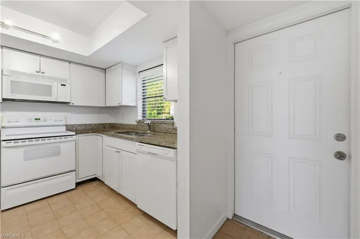 Kitchen featuring white cabinetry, a built-in microwave, white electric range, and light-toned stone countertops