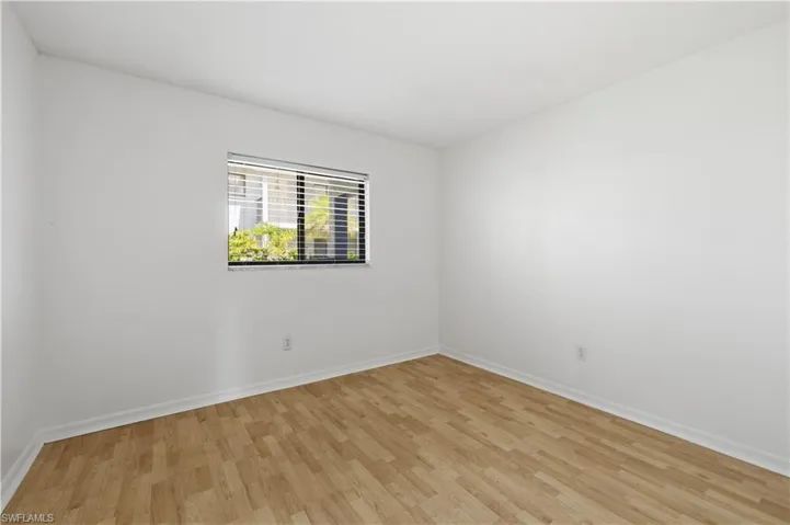Bright room featuring wood-finish flooring, white walls, and a window with horizontal blinds