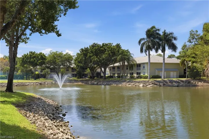 Waterfront property featuring a fountain, established trees, and lush landscaping