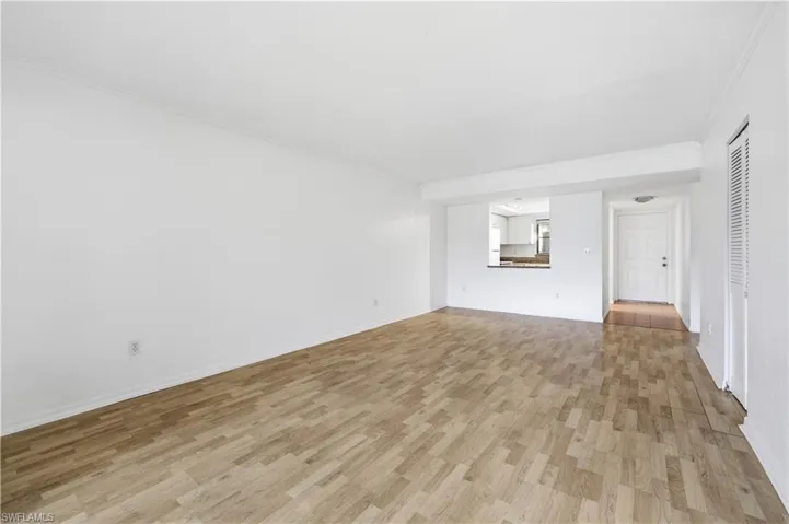Spacious living area featuring wood-finish flooring, white walls, and crown molding