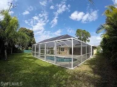 View of pool with glass enclosure and a lawn