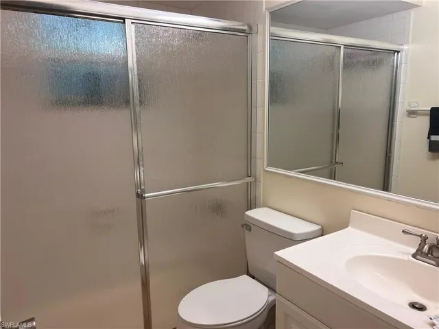 Bathroom featuring toilet, vanity, and walk in shower