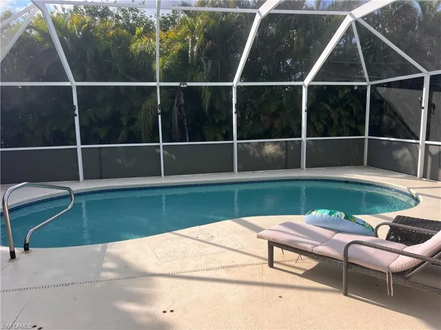 View of pool featuring a patio and glass enclosure