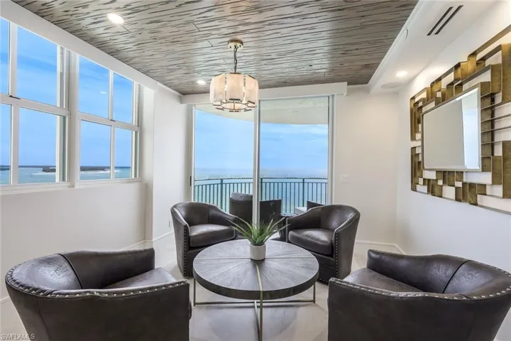 Living area featuring a water view, healthy amount of natural light, wooden ceiling, recessed lighting, and a chandelier