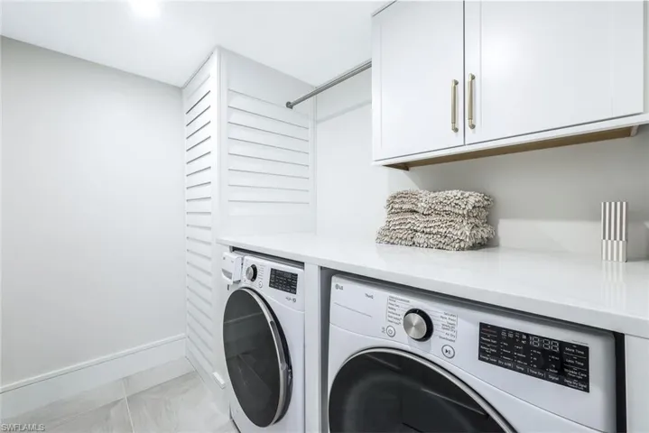 Laundry room featuring cabinet space, independent washer and dryer, and light tile patterned floors
