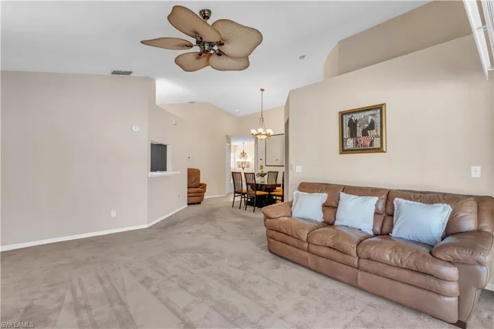 Living room with light carpet, lofted ceiling, and ceiling fan with sliders to lanai