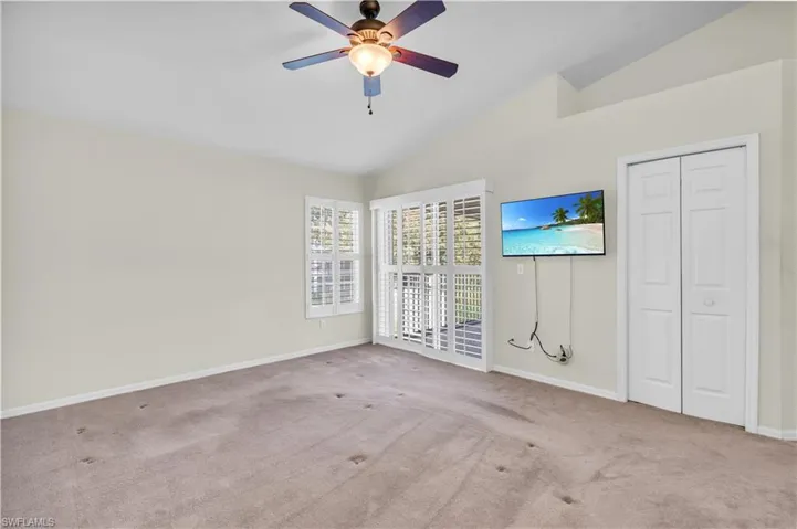 Primary room with vaulted ceiling, light carpet, and ceiling fan. Needs new carpet