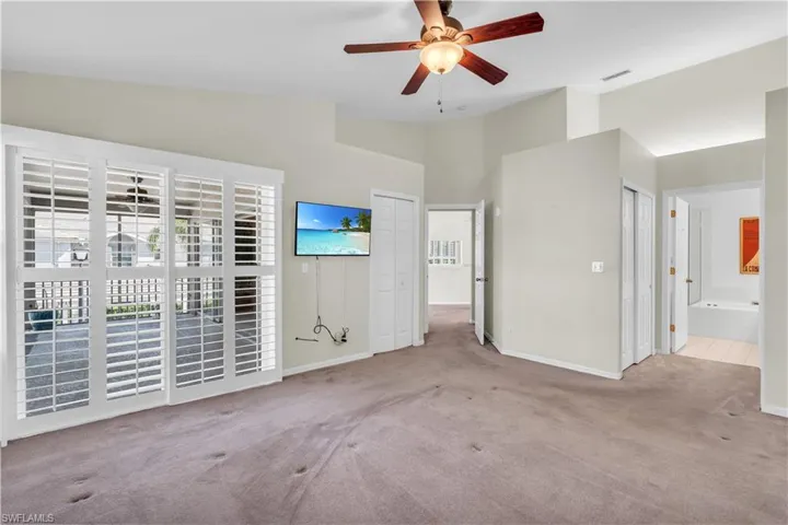 Primary room with vaulted ceiling, light carpet, and ceiling fan. Needs new carpet