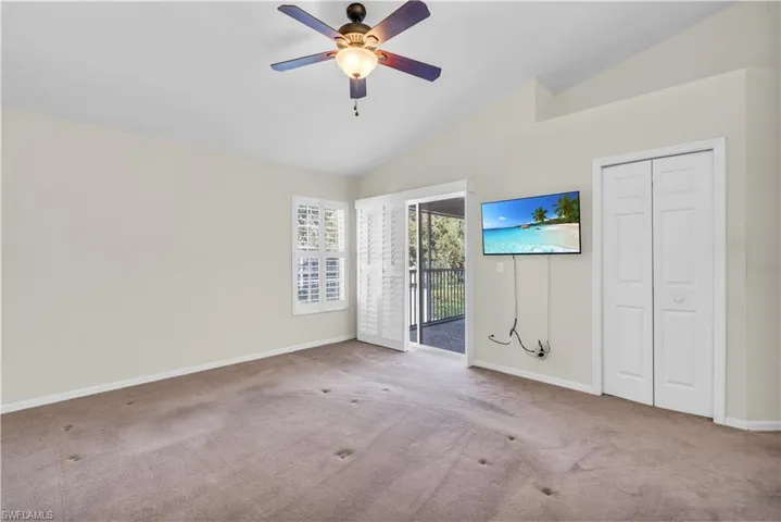 Primary room with vaulted ceiling, light carpet, and ceiling fan. Needs new carpet.