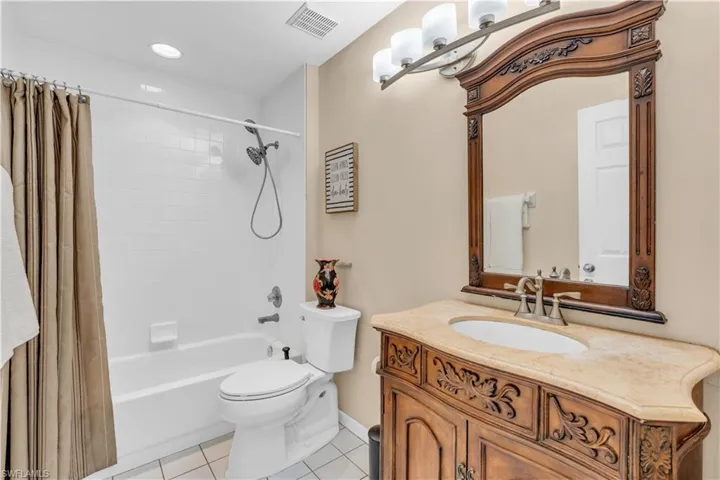 Full bathroom featuring toilet, shower / tub combo with curtain, vanity, and tile patterned floors