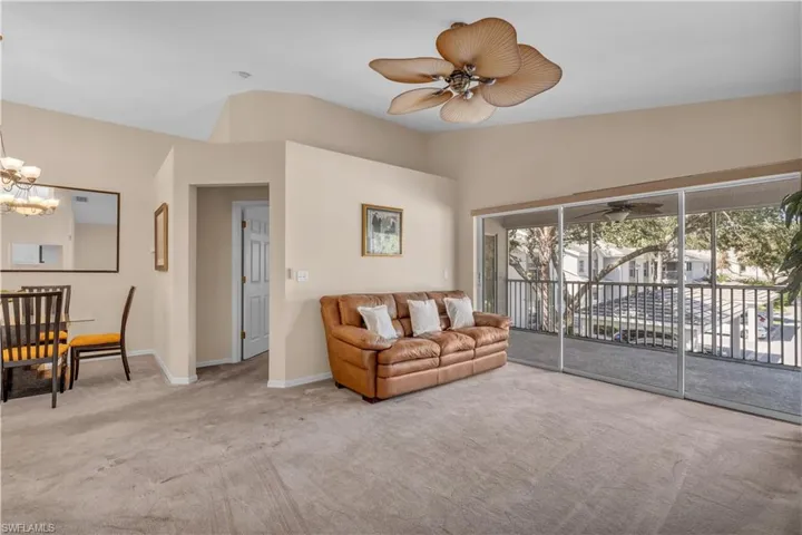 Living room featuring light carpet, vaulted ceiling, and ceiling fan with notable chandelier