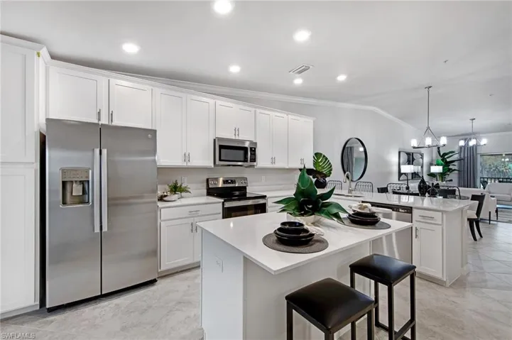 Kitchen featuring stainless steel appliances, white cabinetry, a breakfast bar, a center island, and lofted ceiling