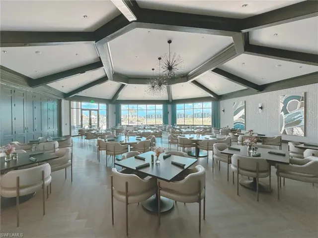Dining room with light wood-style flooring, suspended lighting, beamed ceiling, and plenty of natural light