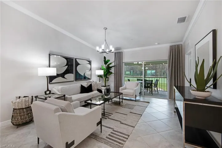 Living room with lofted ceiling, crown molding, suspended lighting, and light tile patterned flooring
