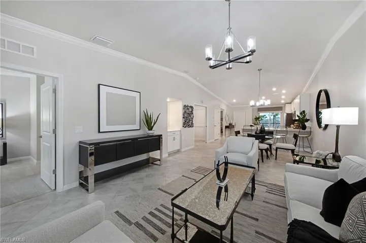 Living room featuring ornamental molding, a chandelier, lofted ceiling, and light tile patterned flooring