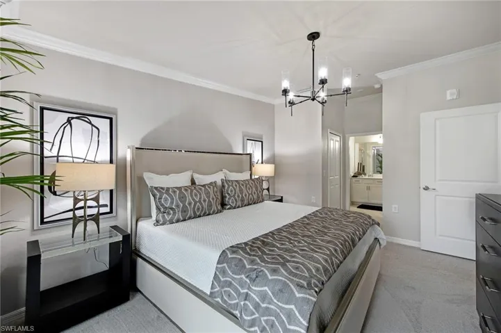 Bedroom featuring connected bathroom, crown molding, light carpet, and hanging lights