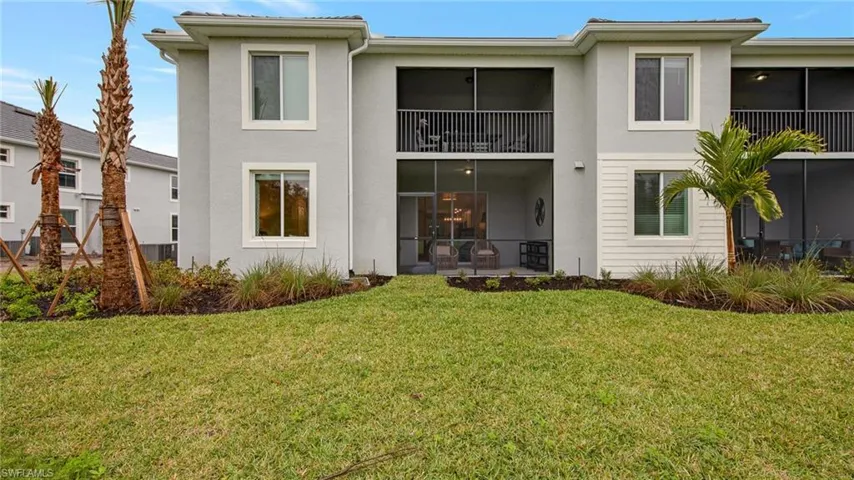 Rear view of house with a sunroom, stucco siding, a balcony, and a yard