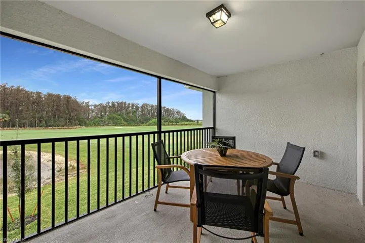 Sunroom / solarium with view of golf course, a balcony, view of scattered trees, and outdoor dining area