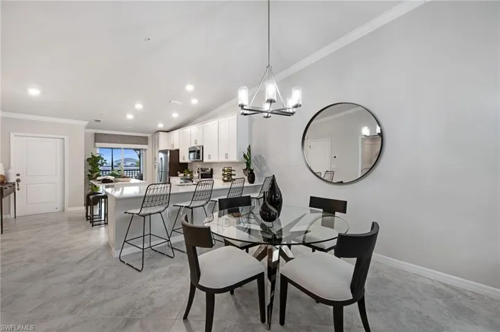 Dining area featuring lofted ceiling, crown molding, and a chandelier