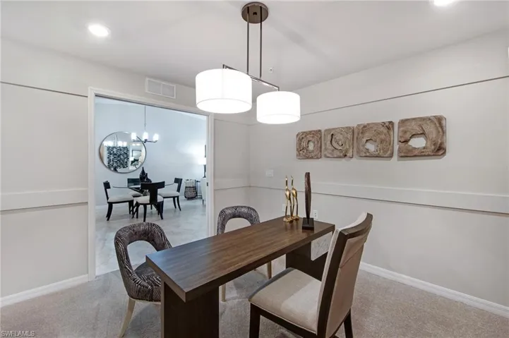 Dining space with hanging lights and light colored carpet