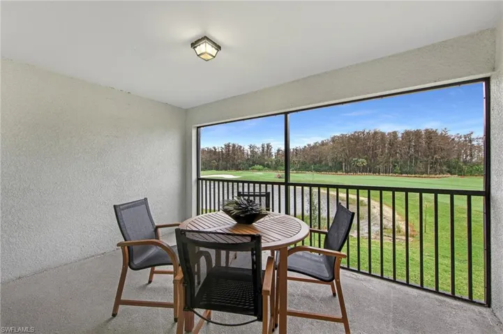 Sunroom / solarium featuring view of golf course and a balcony