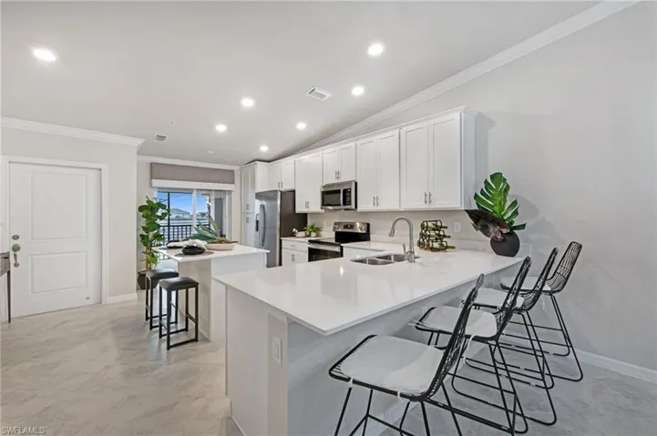 Kitchen with a breakfast bar area, a center island, ornamental molding, a peninsula, and lofted ceiling
