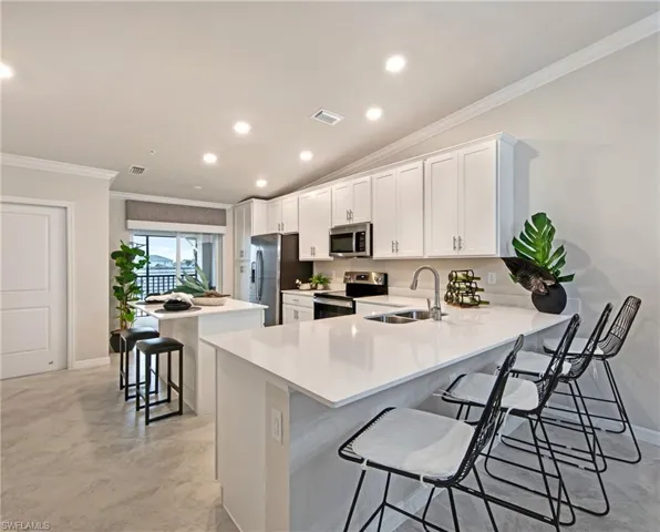 Kitchen with a kitchen breakfast bar, a center island, crown molding, stainless steel appliances, and a peninsula