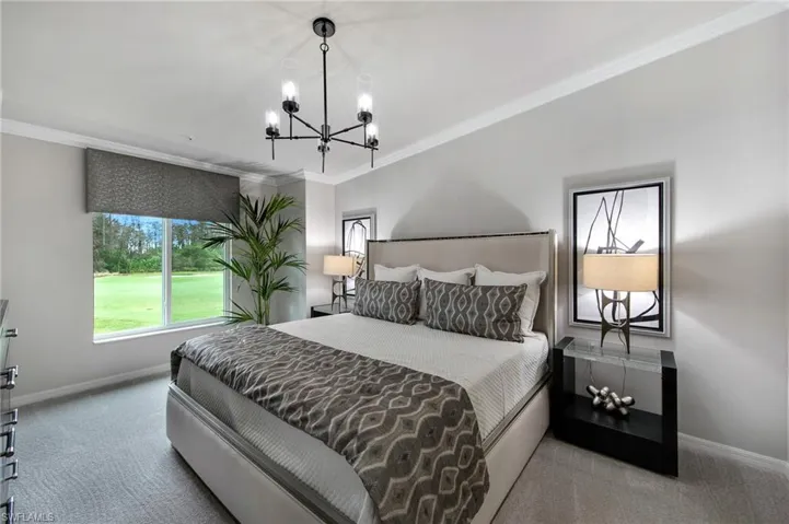 Bedroom with ornamental molding, carpet, suspended lighting, and golf course view