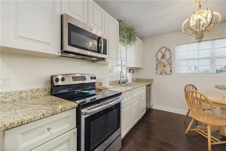 Kitchen with stainless steel appliances, dark wood-type flooring, sink, and a wealth of natural light