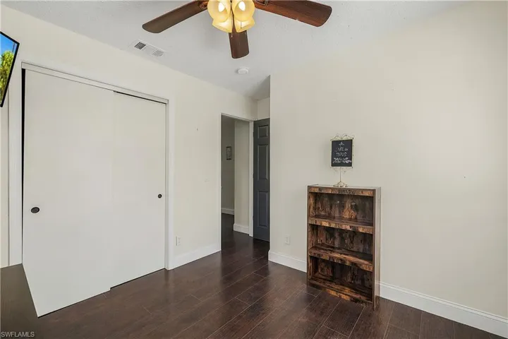 Bedroom featuring dark lamina/ wood-style floors, a closet, and ceiling fan