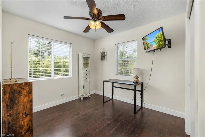 Office space with ceiling fan, dark hardwood / wood-style flooring, a textured ceiling, and a wealth of natural light