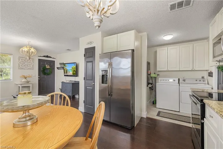 Dining space featuring washing machine and dryer, dark hardwood / wood-style floors, a textured ceiling, and a chandelier