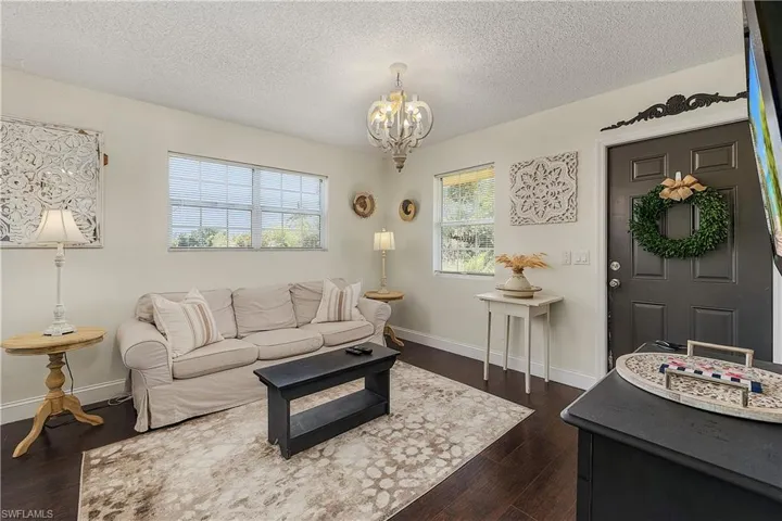 Living room featuring dark hardwood / wood-style flooring, a textured ceiling, and a chandelier