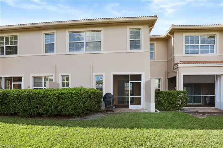 Rear view of property featuring a sunroom, stucco siding, a patio, a yard, and a tiled roof