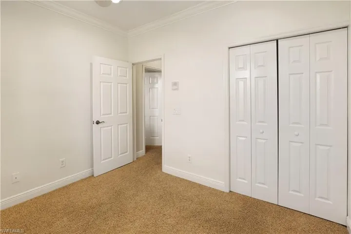 Third bedroom with ornamental molding, carpet, and a closet