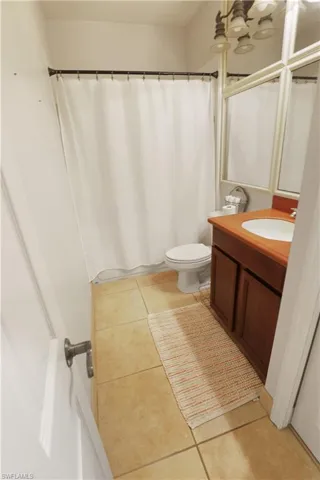 Full bathroom with vanity, a shower with shower curtain, and light tile floors