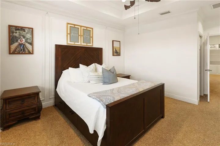 Bedroom with crown molding, light carpet, a raised ceiling, and ceiling fan