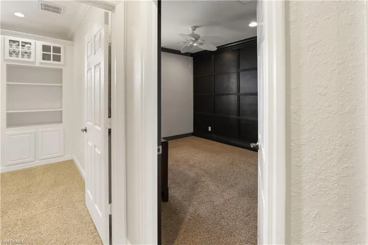 Hallway with light carpet, built in shelves, recessed lighting, and crown molding