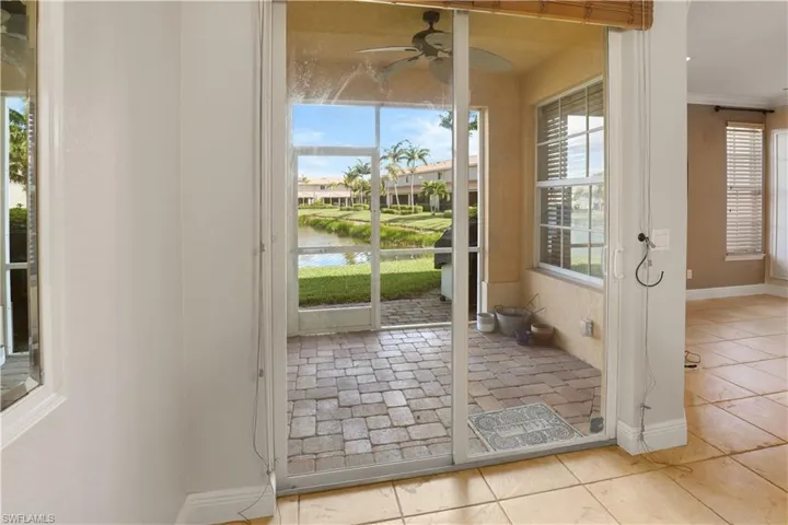 Back lanai featuring a water view, ceiling fan, tile patterned floors, and crown molding