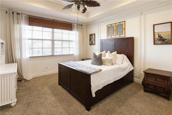 Bedroom featuring ornamental molding, carpet floors, ceiling fan, and a raised ceiling