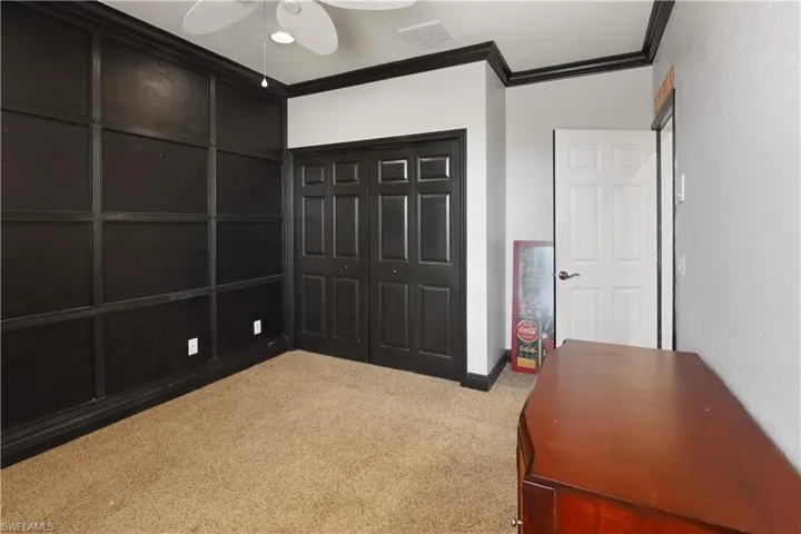 Guest bedroom with ornamental molding, carpet flooring, ceiling fan, and a closet
