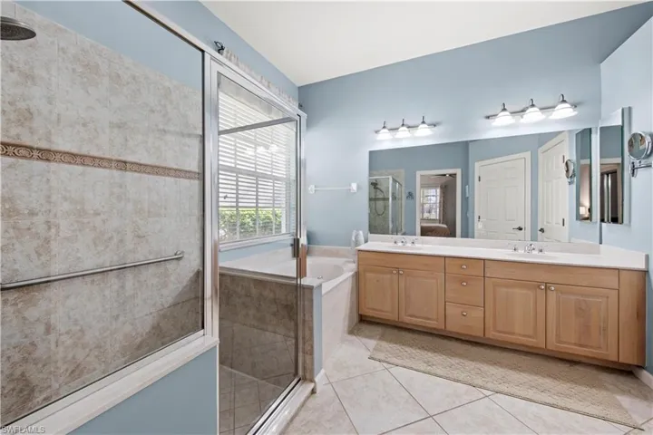 Bathroom with a shower stall, double vanity, a bath, and light tile patterned floors