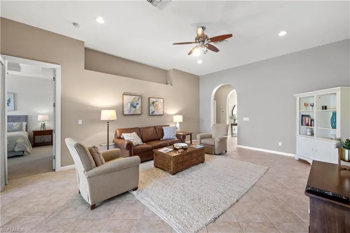 Living area featuring arched walkways, light tile patterned flooring, recessed lighting, and a ceiling fan